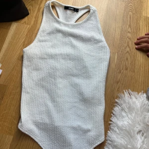 Vit ribbad linnetopp från Bik Bok - Säljer en vit ribbad linnetopp från Bik Bok i storlek S. Toppen har brottarrygg och är tillverkad i ett mjukt material med struktur.