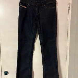 Diesel Lowky mörkblå jeans W25 L32 - Mörkblå jeans från Diesel, modell Lowky alltså bootcut. Klassisk femficksdesign med snygga kontrastsömmar och dragkedjor som bakfickor. Väldig snygga jeans men är för små för mig.