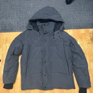 Vinterjacka canada goose  - Säljer en mörkgrå dunjacka från Canada Goose med huva och klassisk logga på ärmen. Jackan använd förra och förrförra vintern, bra skick, ihopsydd. Perfekt för kalla dagar och riktigt snygg till olika stilar. Säljer för jag vill köpa en annan vinterjacka, kan gå ner i pris.