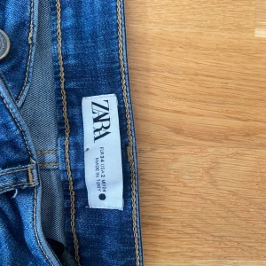 Blå bootcut jeans från Zara - Snygga blå jeans från Zara i klassisk bootcut-modell. Jeansen har fem fickor, normal passform och är tillverkade i mjukt denimtyg med lite stretch. Perfekt för dig som gillar en tidlös look med lite utsvängda ben. Midjan är normal och färgen är mörkblå.