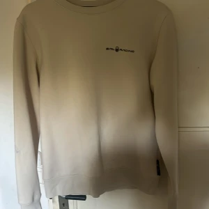Beige Sail Racing sweatshirt i M - Snygg beige sweatshirt från Sail Racing i storlek M. Tröjan har en stilren look med diskret logga på bröstet och en liten logga i nacken. Rund hals och långa ärmar, perfekt för chill dagar. Mjuk bomullskänsla och klassisk passform.