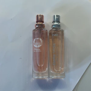 NG Dominatio & Bella Vida parfym duo - Två eleganta parfymflaskor från NG: Dominatio Woman och Bella Vida. Båda har cylinderformade glasflaskor med rosa-beige toner, en med roséguldfärgad och en med silverfärgad spraykork. Perfekt för dig som gillar stilrena och feminina dofter. 10kr styck 17kr för båda! 15ml💗