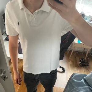 Vit piké från Ralph Lauren - Vit pikétröja från Ralph Lauren med klassisk krage och korta ärmar. Storlek XL i barn men sitter som S. Små fläckar på ryggen, se bild 3