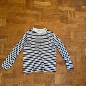Randig långärmad tröja från Weekday - Säljer en klassisk långärmad tröja från Weekday med svartvita horisontella ränder. Tröjan har rund hals och är gjord i mjuk bomull, perfekt för chill dagar. Enkel och stilren design som funkar till jeans eller shorts.