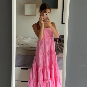 Rosa långklänning - Säljer en superfin rosa långklänning från Collusion med volanger och axelband. Klänningen har en luftig och flowy passform, perfekt för varma dagar. Materialet är mjuk bomull och modellen har tunna justerbara band 