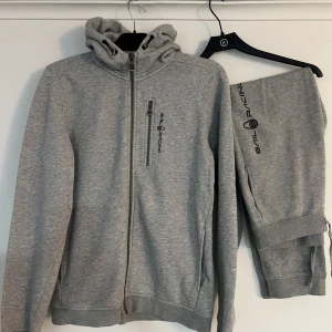 Grått Sail Racing set - Säljer ett grått set från Sail Racing. Nyskick bägge två, inget slitage el hål överhuvudtaget. Hoodien i strl 176 och byxorna i strl 160-170. Kan även säljas separat!