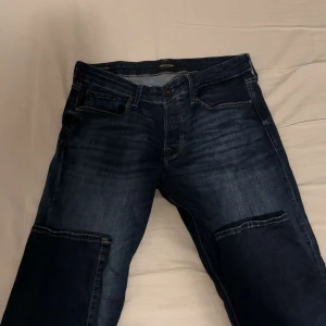 Mörkblå jeans med cargodetaljer, stl 34/34 - Säljer ett par mörkblå jeans med coola cargofickor på benen. Jeansen har klassisk femficksdesign, kontrastsömmar och en rak passform. Materialet är slitstarkt denim och färgen har snygga tvättade detaljer. Perfekt för dig som gillar streetwear och vill sticka ut.