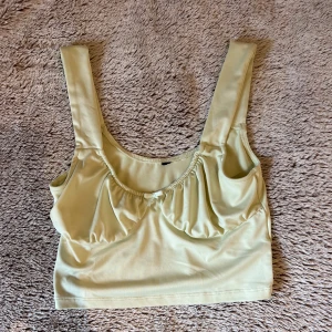 Ljusgrön croppad linnetopp med rosett  - Ljusgrön crop top med breda axelband och rynkad detalj framtill. Köpt på hm och är storlek S. 