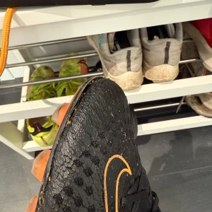 Svarta Nike fotbollsskor med orange detaljer - Svarta Nike fotbollsskor