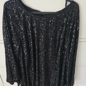 Svart glitter klänning  - Glittrig svart klänning från H&M i storlek L, täckt med paljetter för maxad partykänsla. Modellen har trekvartsärm och rund halsringning, samt en snygg öppning i ryggen. Perfekt för dig som vill sticka ut och glänsa.