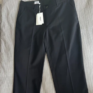 Oanvända Svarta kostymbyxor,  Filippa K - Stilrena svarta kostymbyxor från Filippa K med klassisk rak passform och pressveck. Byxorna har midwaist, sidfickor och hällor för bälte. Materialet är mjukt och känns lyxigt, perfekt för en clean och snygg look. Passar dig som gillar minimalistisk stil. Original priset är 1 400 kr, säljer för hälften.