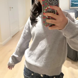 Grå stickad tröja  - Mysig grå stickad tröja med rund hals och ribbade muddar vid ärmslut och nederkant. Perfekt för dig som gillar enkel och stilren look. Långärmad modell med normal passform, passar till jeans eller andra favoritplagg.