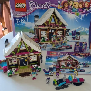 LEGO Friends 41323 - Snow Resort Chalet - Bygg en mysig vinterstuga och lek med Andrea och Amy från LEGO Friends! Använd din fantasi mha medföljande snöskoter, gulliga djur, skiddställ och massor av roligheter i stugan. Perfekt för dig som gillar Lego och med en kraktiv hjärna! Extra bra eftersom du kan leka inne i huset utan problem! Passar dig som letar present till någon annan eller dig själv! Finns inget bättre än att en kall vinterdag sitta med legofriends! Plus är det inte skönt att vara tidig med julklapparna! Legot är komplett!🫶🏻