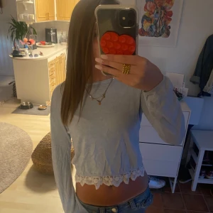 Ljusblå croppad tröja med spets från H&M - Supersöt ljusblå croppad tröja från H&M med lång ärm och spetsdetalj längs nederkanten. Tröjan har en öppen rygg med snygg cutout och är perfekt för dig som gillar en chill men ändå feminin stil. Passar till jeans eller kjol för en fräsch look.