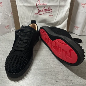 Christian Louboutin svarta sneakers med nitar - Svarta sneakers från Christian Louboutin med coola svarta nitar på tån och klassisk röd sula med logga. Säljer dem för de inte passade mig för stora. Kvitto finns💕du får även med orginal lådan med en påse (den i bakgrunden av varje bild) ☺️snabb affär då dem ligger uppe billig för deras skick (ALDRIG ANVÄNDA). Pris kan diskuteras