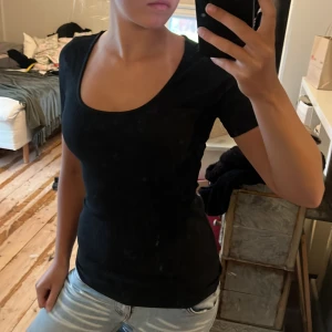 Svart ribbad T-shirt  - Svart ribbad topp istorlek XS. Modellen har rundad, djup halsringning och korta ärmar. Materialet är mjukt och stretchigt. Passformen är tight och toppen är enkel att stylea💕