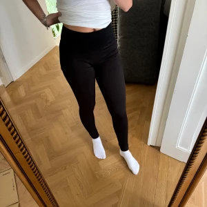 Svarta ribbade leggings från casall  - Säljer ett par svarta leggings med ribbad struktur och hög midja. De är tighta och sitter snyggt på kroppen, perfekta för chill eller träning. Materialet är mjukt och stretchigt, vilket gör dem riktigt sköna att ha på sig hela dagen.