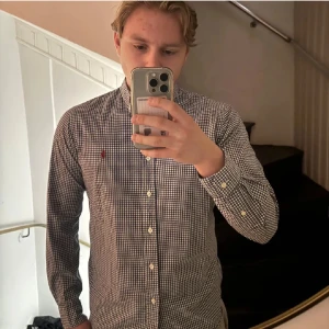 Rutig blå skjorta från Ralph Lauren - Snygg rutig skjorta från Ralph Lauren i slim fit med klassisk krage och knappar hela vägen. Skjortan är blå och vit med det ikoniska röda Polo-logot broderat på bröstet. Tillverkad i mjuk bomull med stretch för extra komfort.