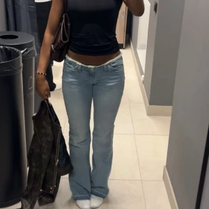 Ljusblå bootcut jeans med rå kant - Säljer ett par ljusblå jeans med bootcut passform och låg midja. Köpte för 699kr endast använda en gång