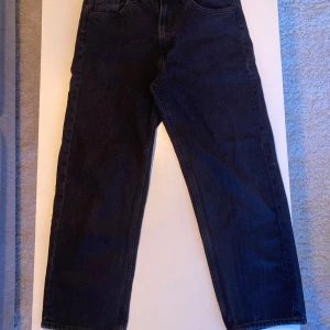 Svarta jeansbyxor - Säljer ett par klassiska svarta jeansbyxor med baggy passform. Byxorna har en traditionell femficksdesign och är perfekta för en stilren look. De är tillverkade i ett slitstarkt material som ger en bekväm känsla hela dagen. Kolla gärna in mina andra annonser!
