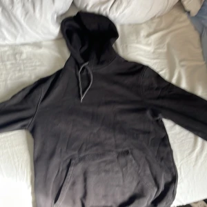Svart hoodie från Divided - Säljer en svart hoodie från Divided i storlek S men passar m. Den har en klassisk design med huva och en stor ficka framtill. Perfekt för en avslappnad stil. Hör av dig vid intresse! Det står xs men jag är m o den passar mig perfekt 