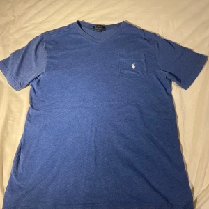Blå och röd t-shirt från Polo Ralph Lauren - Två snygga t-shirts från Polo Ralph Lauren i blått och rött. Båda har en v-ringning och en liten bröstficka med broderad logga. Perfekta för en avslappnad stil.