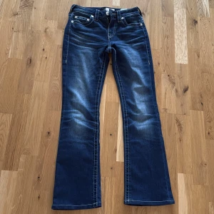 True Religion Jeans Becca - Snygga blå jeans från True Religion i modellen Becca. Jeansen har en medelhög midja.  Förra ägaren har sytt upp längden på jeansen hos skräddare. Jag är 161/162 cm och de passar perfekt i längden. 