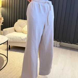 Beige mjukisbyxor med dragsko - Säljer ett par bekväma beige mjukisbyxor med elastisk midja och dragsko. Byxorna har en loose passform och är perfekta för en avslappnad stil. De är tillverkade i ett mjukt material som ger en skön känsla. Passarna perfekt som oversize modell (s/m/l storlek).👌🌸🌸