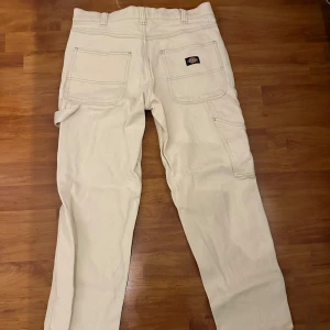 Beige cargopants från Dickies - Säljer ett par beige cargopants från Dickies med flera praktiska fickor och en avslappnad passform. Använt en gång. Storlek: W31/L32
