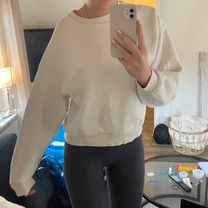 Vit sweatshirt - Säljer en stilren vit sweatshirt med rund hals och långa ärmar. Perfekt för en avslappnad look. Tröjan har ribbade muddar vid ärmslut och nederkant.