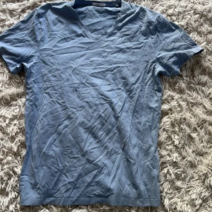 Blå v-ringad t-shirt från bläck - Snygg blå t-shirt från bläck med v-ringning. Perfekt för en avslappnad stil. Tillverkad i mjukt material som känns skönt mot huden.