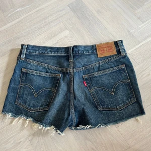 Mörkblå Jeansshorts från Levi's - Säljer ett par klassiska jeansshorts från Levi's i mörkblå denim. De har en knappgylf, Lågmidjade super fina! Midjemått 84, modell 501, storlek 28