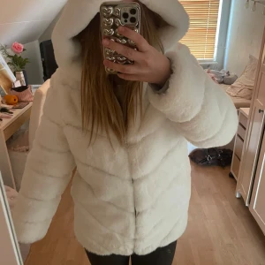 Vit pälsjacka från Garoff - Säljer en supermjuk och fluffig vit pälsjacka från Garoff. Jackan har en stor huva och stängs med dragkedja. Perfekt för kyliga dagar när du vill känna dig extra mysig och stilren.