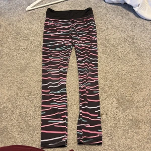 Färgglada mönstrade leggings - Säljer ett par färgglada leggings med vågigt mönster i rosa, blått och vitt på svart bakgrund. Ett par perfekta träningsbyxor för barn helt enkelt. Storlek 134-140. 🤍