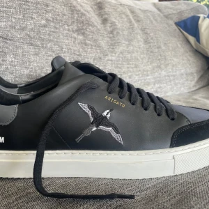 Svarta sneakers från Axel Arigato - Clean 90 Bee Bird Sneaker Black.. Snygga svarta sneakers från Axel Arigato med broderad fågel på sidan. Skorna har en vit sula och svarta snören. Perfekta för en stilren look. Använda 3 gånger= som nya. Nypris ca 2600kr.