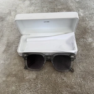 Chimi 04 Grey - Snygga grå solglasögon från Chimi med en fyrkantig form. De har en transparent grå båge och mörka linser. Perfekta för en stilren look.