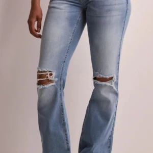 Ljusblå lågmidjade bootcut jeans - Snygga ljusblå bootcut jeans med slitningar på knäna. De köptes i november för 700kr och säljs då de inte kommit till så mycket användning! Pris går att diskuteras 🩷
