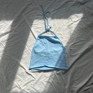 Ljusblå halterneck-topp - Säljer en söt ljusblå halterneck-topp med knytband i nacken. Perfekt för varma sommardagar. 