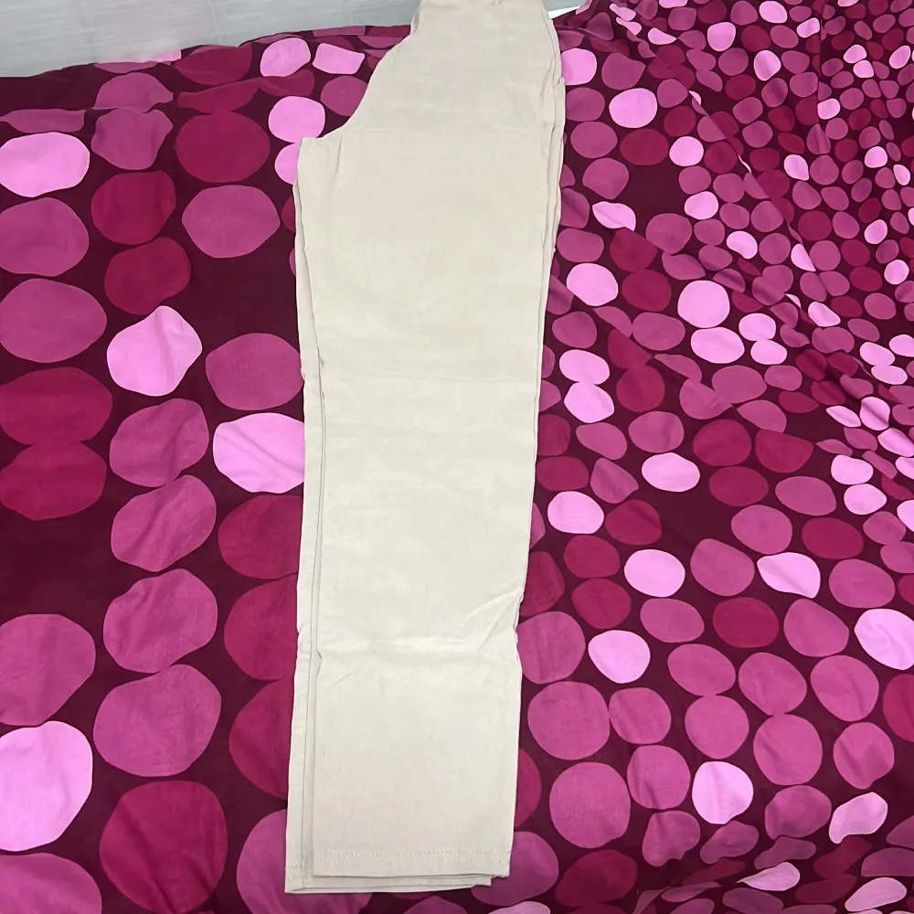Snygga beige kostymbyxor med hög midja och en elegant, smal passform. Perfekta för en stilren look. De är tillverkade i ett mjukt material som ger en bekväm känsla hela dagen.. Farkut & Housut.