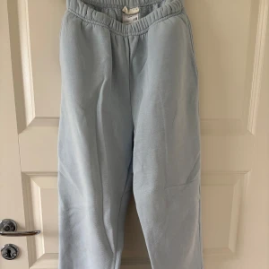 Ljusblå mjukisbyxor från Gina Tricot - Säljer ett par ljusblå mjukisbyxor från Gina Tricot i storlek XS. Byxorna har en elastisk midja. Det finns några små fläckar på botten av benen som inte går bort i tvätten.                                                                       Midjemått rakt över: 29cm                                    Innerbensmått: 70cm                                               Hela benet från midja till botten av benet:90cm
