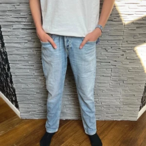 Ljusblå jeans från DonDup - Säljer ett par ljusblå jeans från Dondup med röd detaljsöm vid bakfickan. Jeansen har rak passform och perfekta för en avslappnad och trendig look. Längd 97 cm och bredd 41 cm. Storlek W32. Fraktar oftast samma dag!