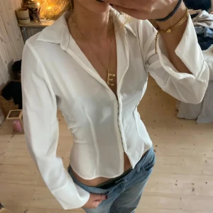 Vit figursydd skjorta med knappar - Snygg vit skjorta med figurnära passform och klassisk krage. Skjortan har långa ärmar och knäppning framtill. Perfekt att styla med jeans för en clean och fräsch look.💕(lånade bilder!)