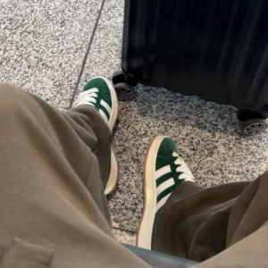 Adidas Campus sneakers grön/vit - Snygga Adidas Campus sneakers i grönt och vitt med klassiska tre ränder på sidan. Skorna har vit platt sula, rund tå och vita skosnören. Till kommer gröna snören, andvönda vid 1 tillfälle som ni ser på bilden Perfekta för dig som gillar retrovibbar och streetstyle.