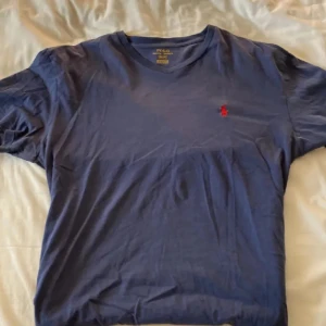 Ralph Lauren T-shirt  - Klassisk Ralph Lauren T-shirt – enkel, stilren och alltid rätt. Tillverkad i mjuk bomull med perfekt passform och den ikoniska broderade ponnyn på bröstet. Passar lika bra till vardags som under en skjorta eller jacka för en mer genomtänkt look. Inga fläckar eller defekter – redo att bäras!