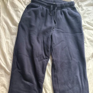 Mörkblå mjukisbyxor med snörning - Mörkblå mjukisbyxor med elastisk midja och snörning. Byxorna har raka ben och är tillverkade i mjukt material som känns skönt mot huden. Perfekta för chill dagar eller när du vill vara extra bekväm.