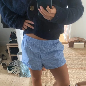 Blå randiga shorts från Zara - Blå randiga  shorts från Zara. De har elastisk midja, sidfickor och bakfickor. Perfekta för varma dagar och chill stunder. Tillverkade i mjuk bomull och kan användas som pyjamas. 