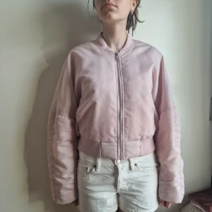 Ljusrosa bomberjacka från Gina Tricot - Säljer en ljusrosa bomberjacka från Gina Tricot i storlek M. Jackan har klassisk bombermodell med ribbade muddar, dragkedja framtill och en riktigt snygg oversized passform. Perfekt för dig som vill ha en chill och trendig look.