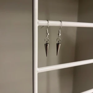 Silvriga konformade örhängen - Steinlesssteal. Ett par coola silvriga örhängen med konformad hängande detalj. De har en minimalistisk och edgy stil som passar perfekt till dig som gillar att sticka ut. Säljs som ett par. Handgjort 