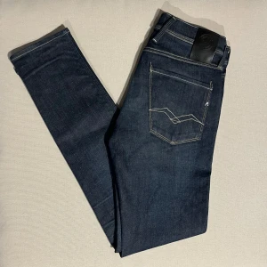 SPRILLANS nya Replay Anbass Hyperflex slim fit  - Helt nya.Snygga mörkblå Replay Anbass jeans med klassisk femficksdesign och kontrastsömmar. Slimmad passform och tillverkade i mjukt jeansmaterial med stretch. Stilsäker detalj med logga på bakfickan och läderpatch i midjan. Perfekta för dig som gillar en modern look.