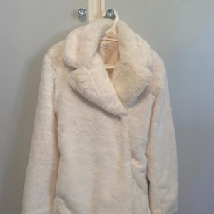 Vit pälsjacka från H&M, strl 164 - Supermjuk och fluffig vit pälsjacka från H&M med bred krage och helfodrad insida. Perfekt för dig som vill ha en stilren och cozy look under kyliga dagar. Jackan har en klassisk rak passform och känns riktigt lyxig.